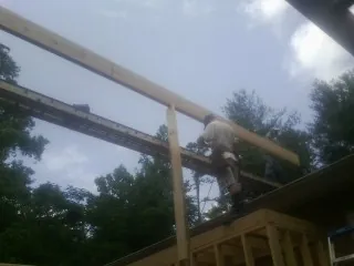 Carpenter setting a ridge beam over a new addition frame — Ice Dam Removal by Roofing Brothers in Burke