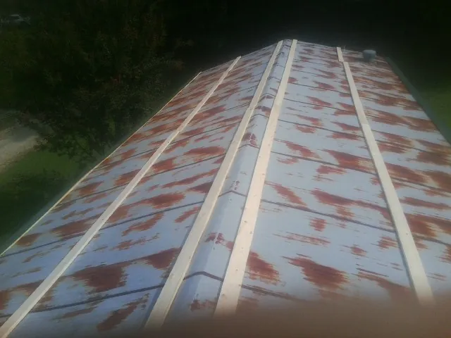Rusted metal roof panels with new wood purlins before replacement in Burke