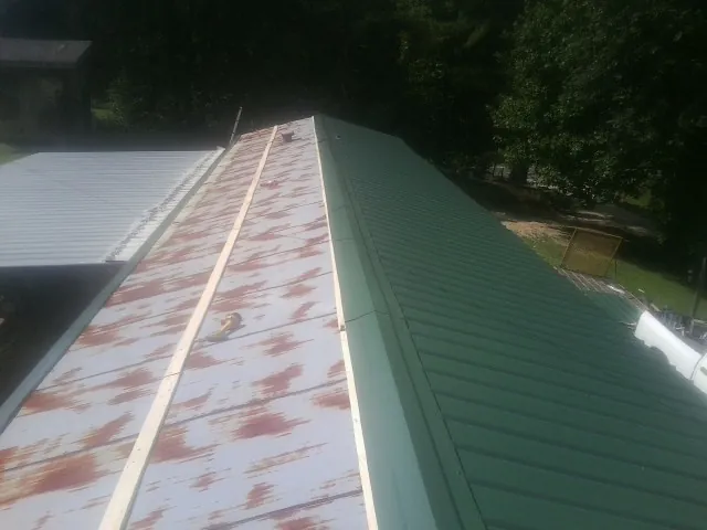 Old rusted panels beside newly installed green metal roofing — Wind Damage Roof Repair by Roofing Brothers in Burke