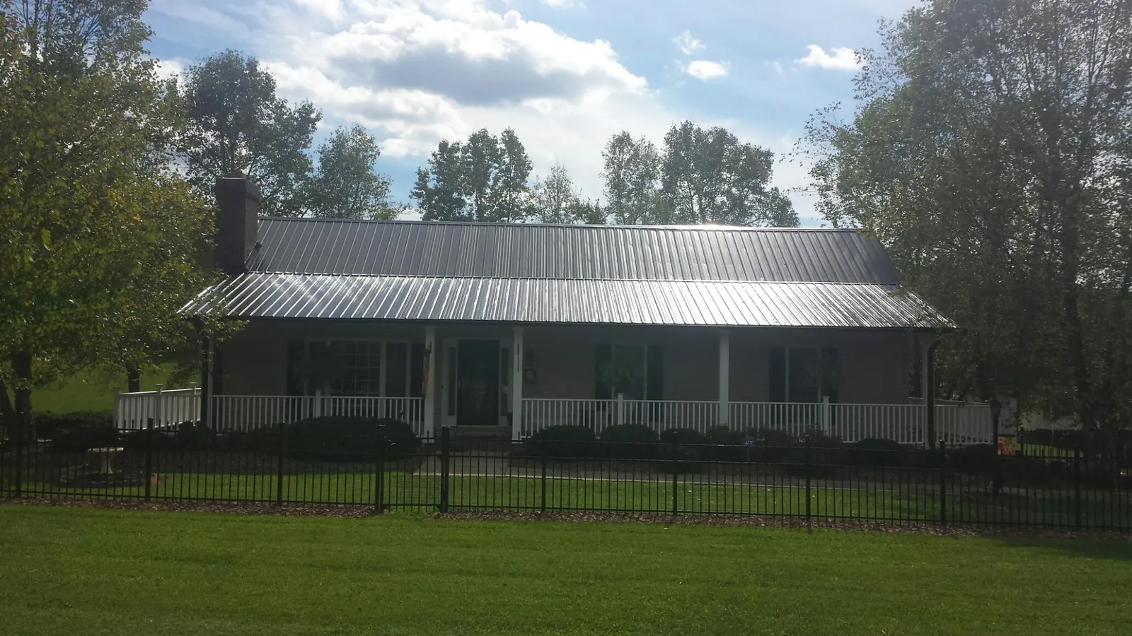 Gray metal roof on a brick ranch with a full width front porch — Gutter Guard Installation work by our crew in Burke