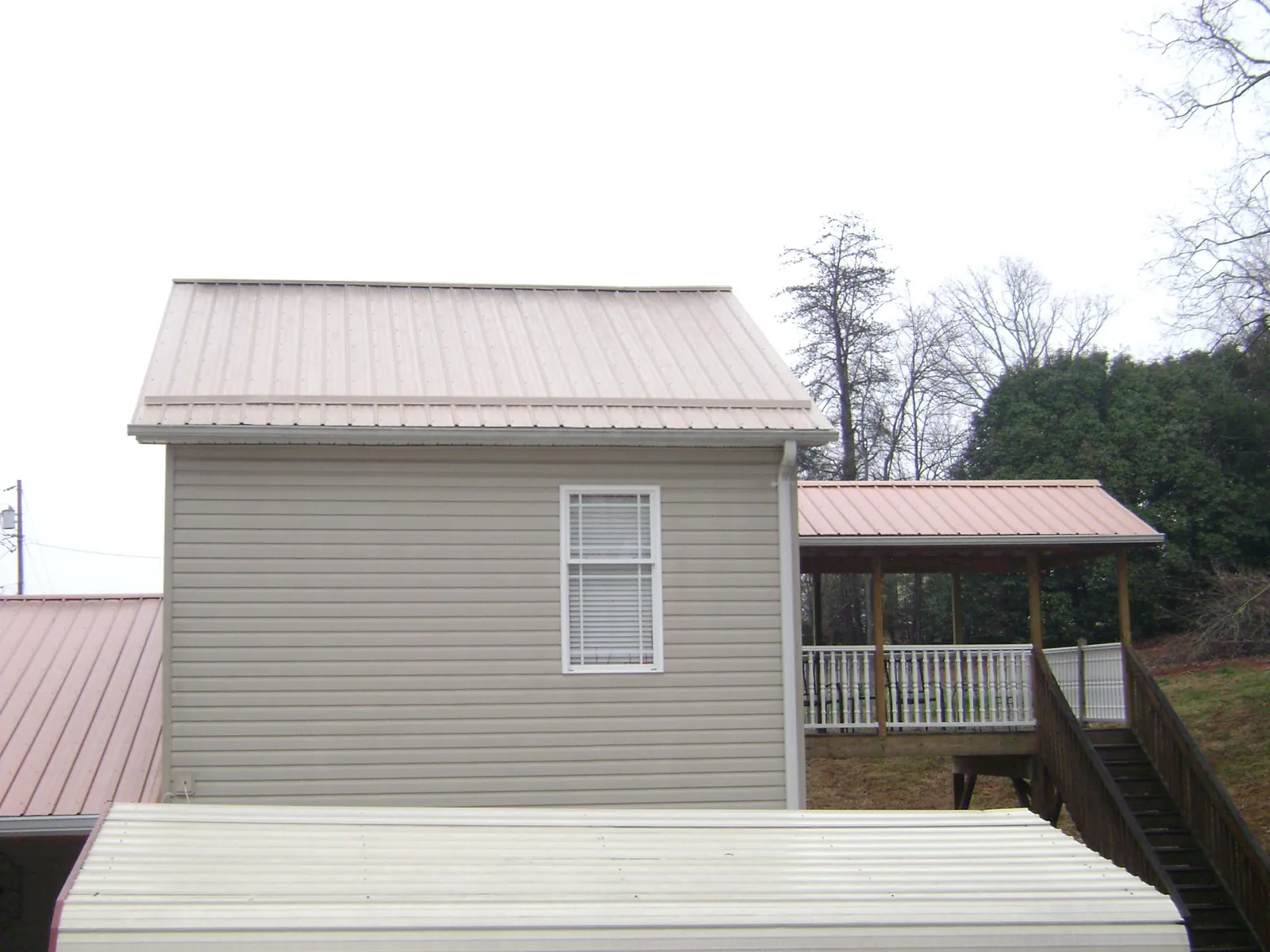 Tan metal roofs on a two story addition and attached porch, from a Roof Replacement job in Burke