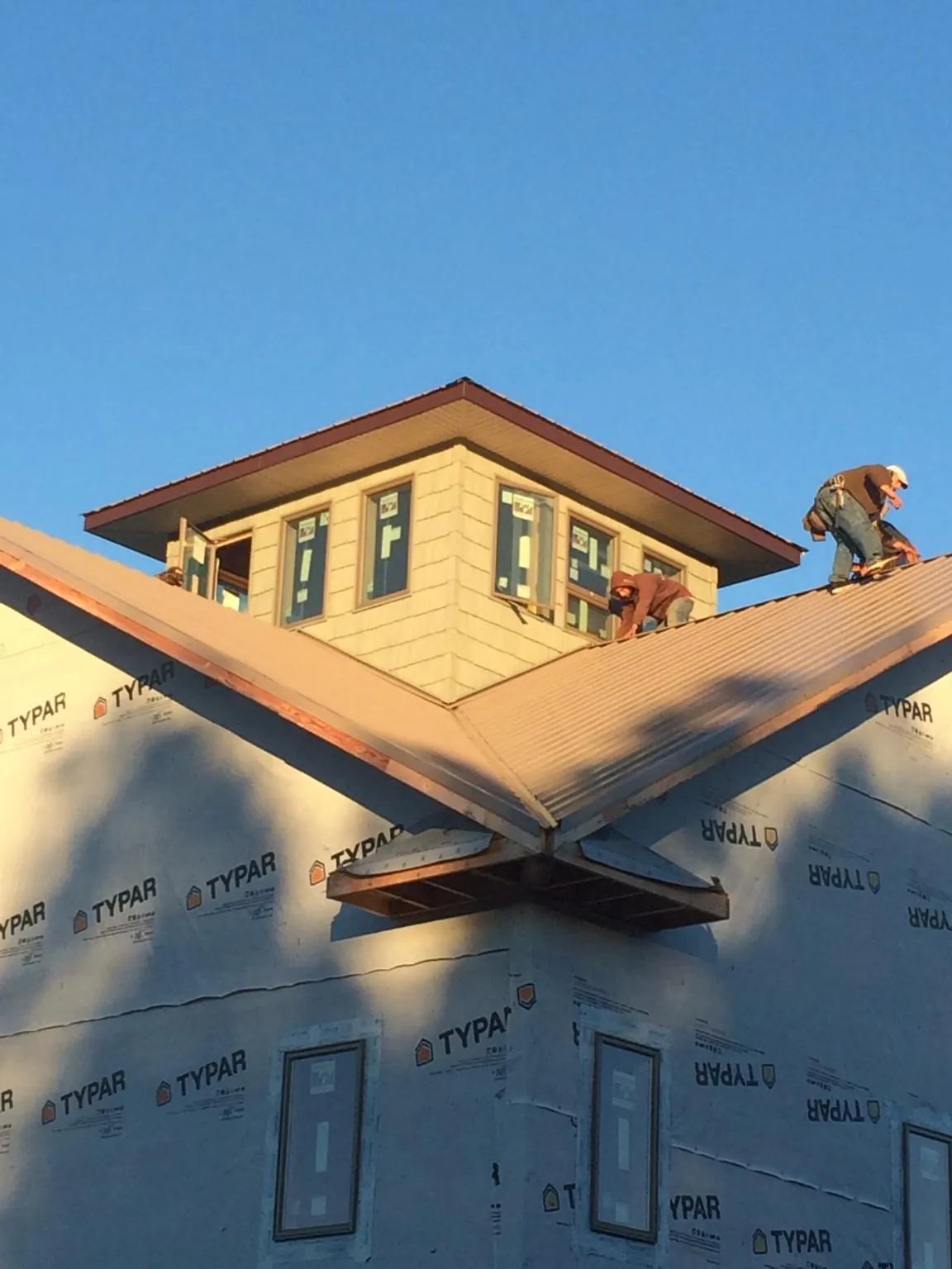 Roofers working around a rooftop cupola on a new metal roof at sunset — Roof Waterproofing in Burke by Roofing Brothers